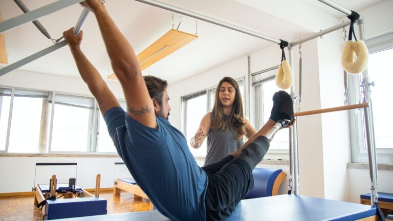 Woman instructing a man on the Pilates apparatus