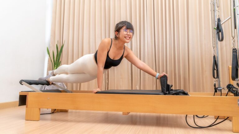 Young woman working on pilates reformer machine