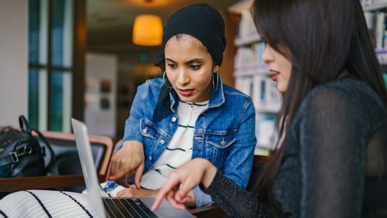 two women looking and pointing at laptop