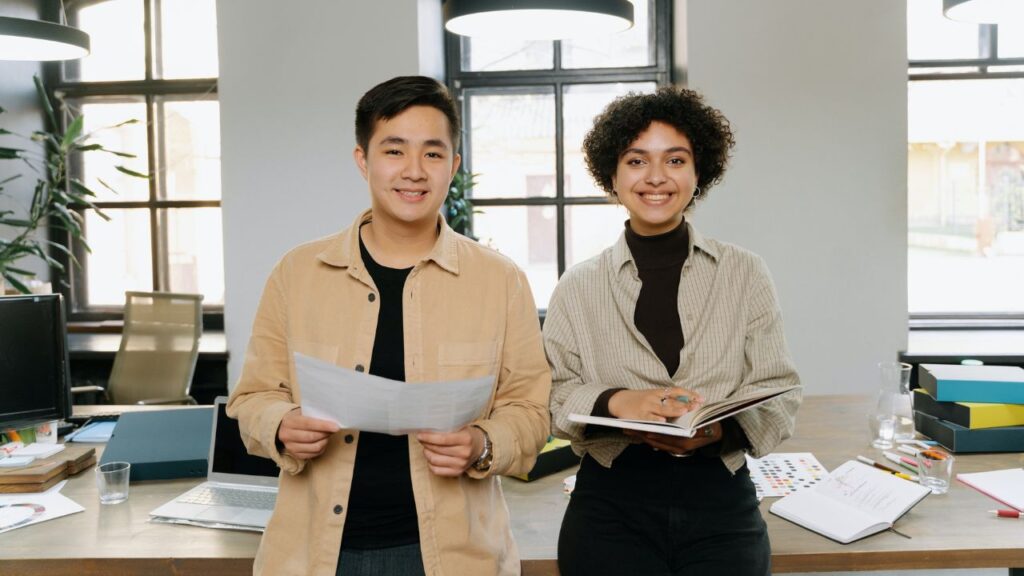 a man holding a document standing beside a woman in an office